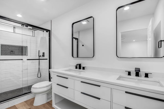 bathroom featuring vanity, hardwood / wood-style flooring, a shower with shower door, and toilet