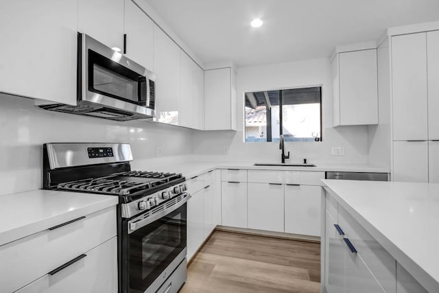 kitchen with white cabinetry, appliances with stainless steel finishes, sink, and light hardwood / wood-style floors