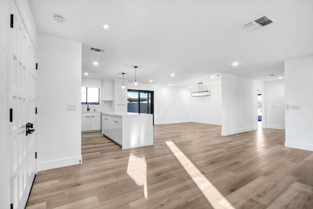 kitchen with white cabinetry, light hardwood / wood-style floors, and decorative light fixtures