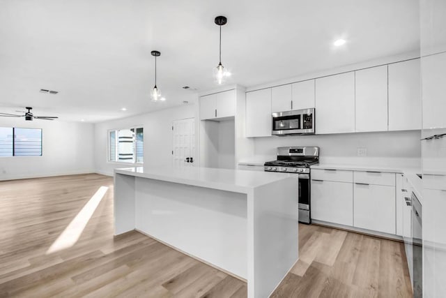 kitchen featuring stainless steel appliances, a center island, pendant lighting, and white cabinets