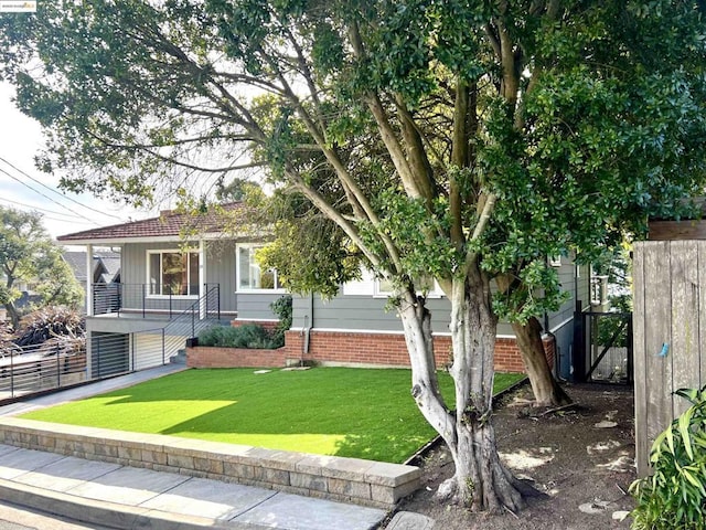 view of property hidden behind natural elements featuring a front lawn