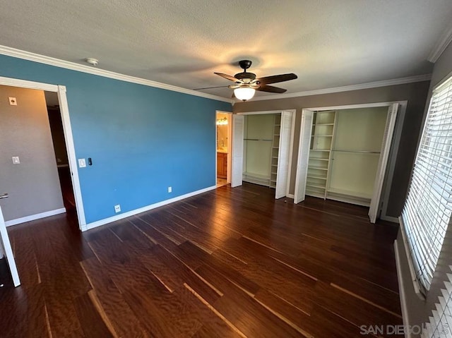 unfurnished bedroom featuring dark wood-type flooring, ornamental molding, a textured ceiling, and two closets