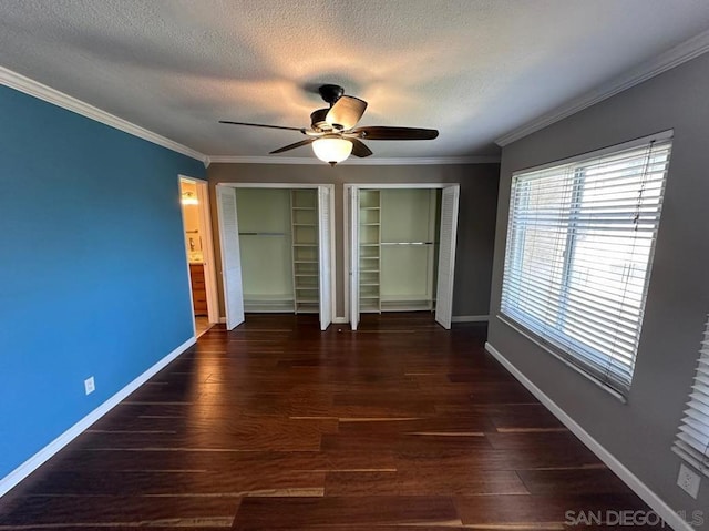 unfurnished bedroom with ornamental molding, dark hardwood / wood-style floors, two closets, and a textured ceiling