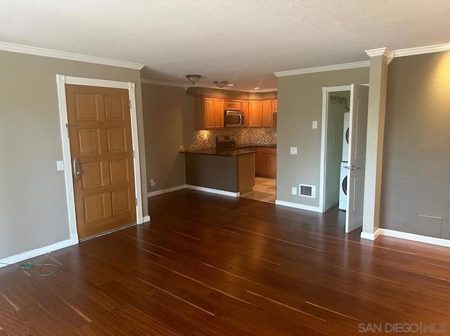 unfurnished living room with crown molding, dark hardwood / wood-style floors, and stacked washing maching and dryer