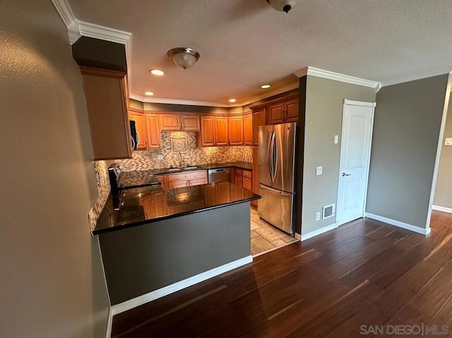 kitchen featuring appliances with stainless steel finishes, ornamental molding, decorative backsplash, kitchen peninsula, and light wood-type flooring