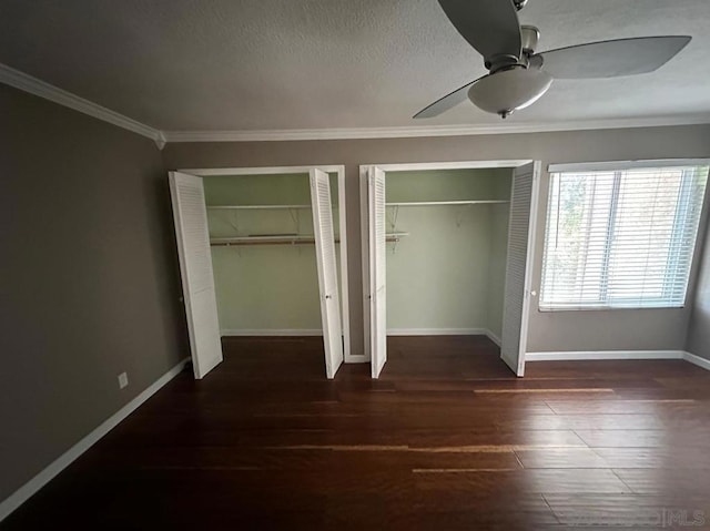 unfurnished bedroom with crown molding, ceiling fan, dark hardwood / wood-style floors, a textured ceiling, and multiple closets