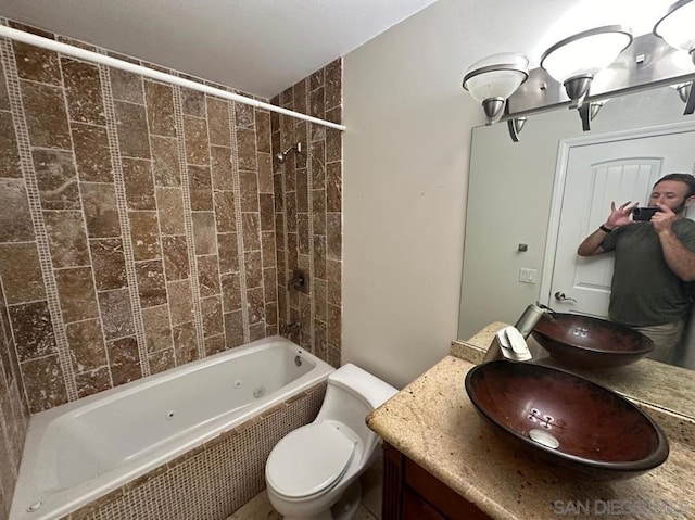 full bathroom with vanity, tiled shower / bath combo, and toilet