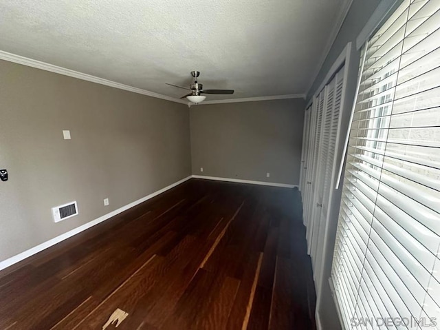 spare room featuring a textured ceiling, dark wood-type flooring, ornamental molding, and ceiling fan