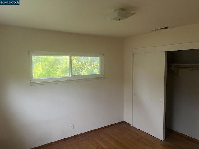 unfurnished bedroom featuring dark wood-type flooring and a closet