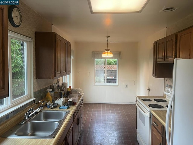 kitchen with sink, pendant lighting, backsplash, and white appliances