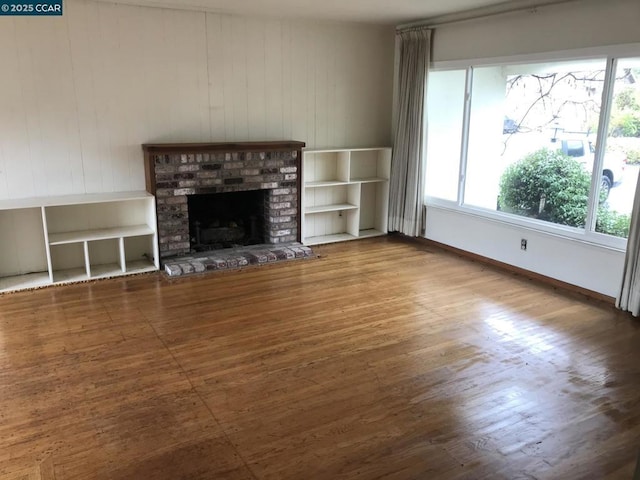 unfurnished living room featuring hardwood / wood-style floors and a brick fireplace