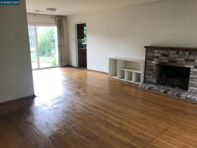 unfurnished living room featuring a brick fireplace and wood-type flooring