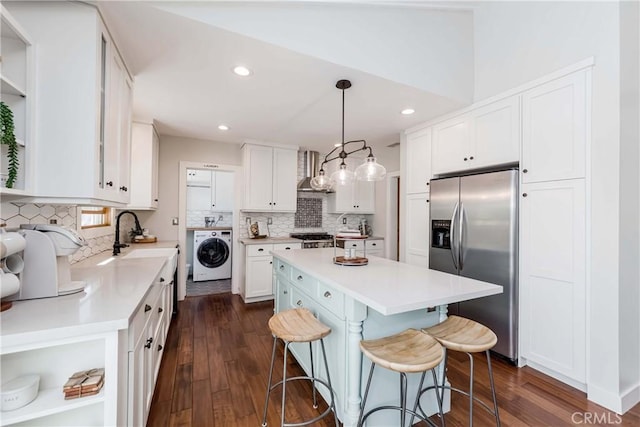 kitchen with white cabinetry, a kitchen island, stainless steel fridge with ice dispenser, washer / dryer, and decorative light fixtures