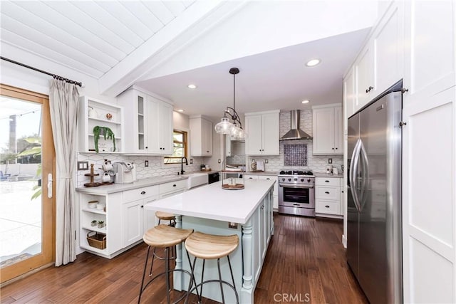 kitchen featuring wall chimney exhaust hood, stainless steel appliances, a center island, and white cabinets