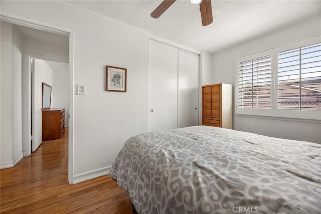 bedroom featuring hardwood / wood-style flooring, ceiling fan, a closet, and a textured ceiling