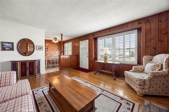 living room featuring wooden walls, a textured ceiling, and light wood-type flooring