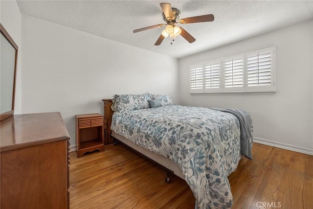 bedroom with ceiling fan, a textured ceiling, and light wood-type flooring