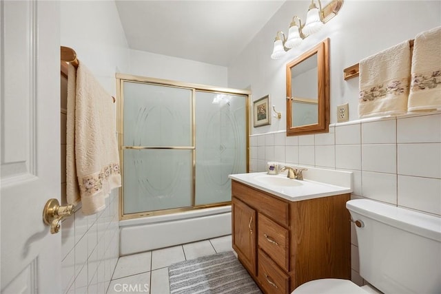 full bathroom featuring shower / bath combination with glass door, tile walls, vanity, tile patterned floors, and toilet