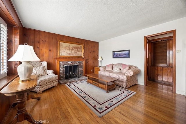 living room with wooden walls, a fireplace, hardwood / wood-style floors, and a textured ceiling