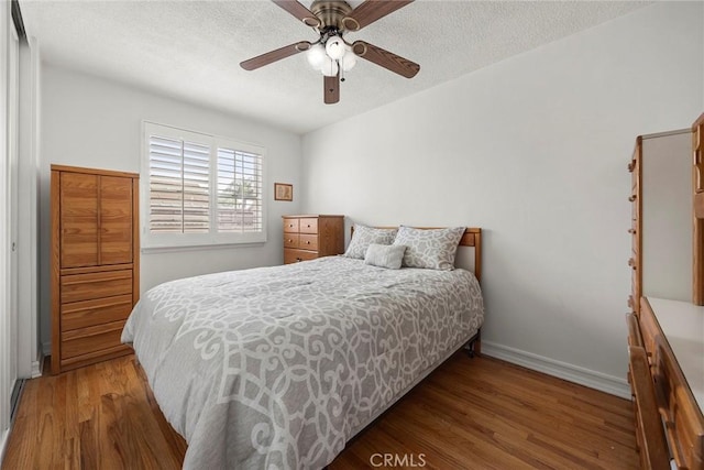 bedroom with ceiling fan, wood-type flooring, and a textured ceiling