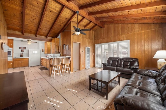 living room featuring wooden walls, light tile patterned floors, ceiling fan, wood ceiling, and beam ceiling