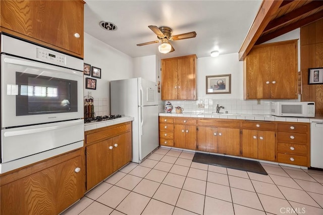 kitchen with tasteful backsplash, white appliances, sink, and light tile patterned floors