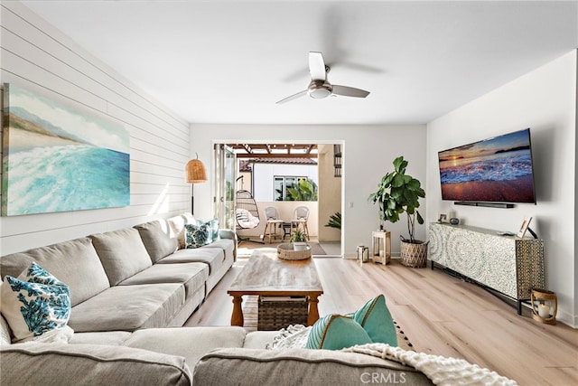 living room with wood-type flooring, wooden walls, and ceiling fan