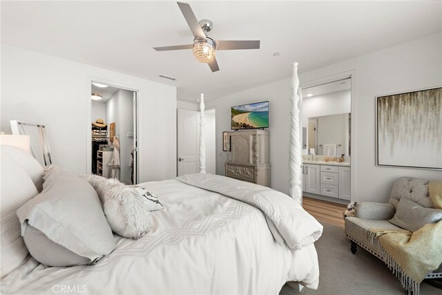 bedroom with ceiling fan, a walk in closet, light hardwood / wood-style floors, and ensuite bath