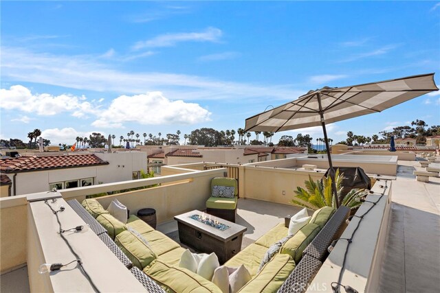 view of patio with an outdoor living space with a fire pit and a balcony