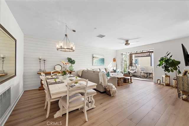 dining area featuring ceiling fan with notable chandelier and light wood-type flooring