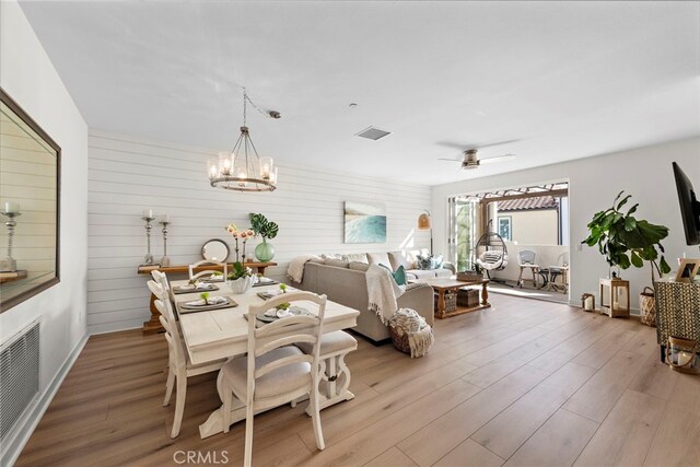 dining area featuring ceiling fan with notable chandelier and light wood-type flooring