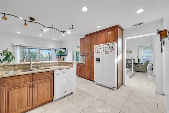 kitchen with light stone counters, white appliances, and sink