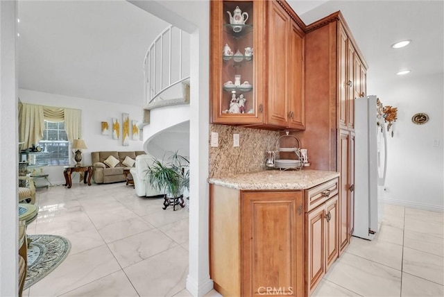 kitchen with white refrigerator, light stone countertops, and tasteful backsplash