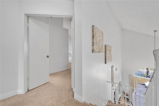 corridor with vaulted ceiling and light colored carpet