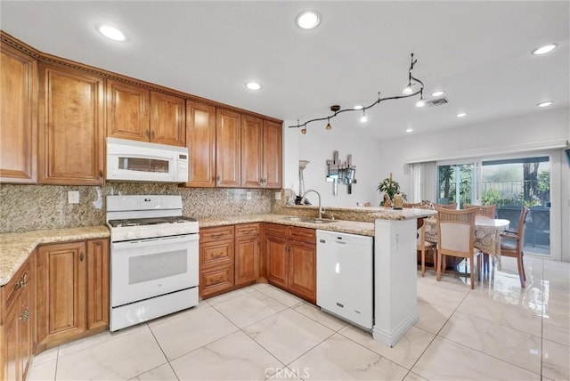 kitchen featuring light stone counters, sink, white appliances, and kitchen peninsula