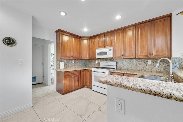 kitchen with sink, white appliances, light stone countertops, and decorative backsplash