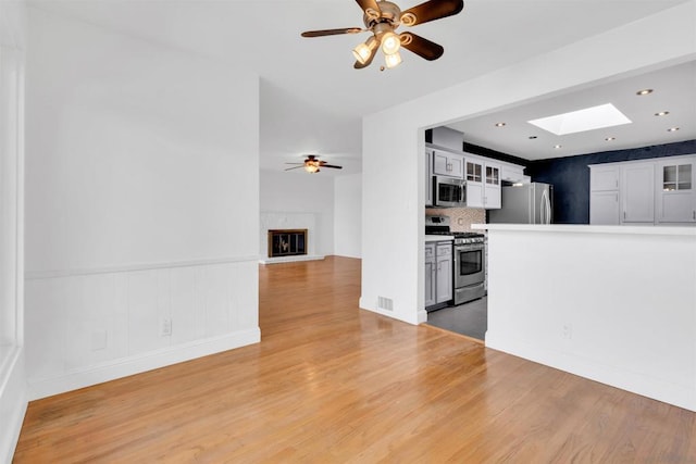 interior space with ceiling fan, wood-type flooring, and a skylight