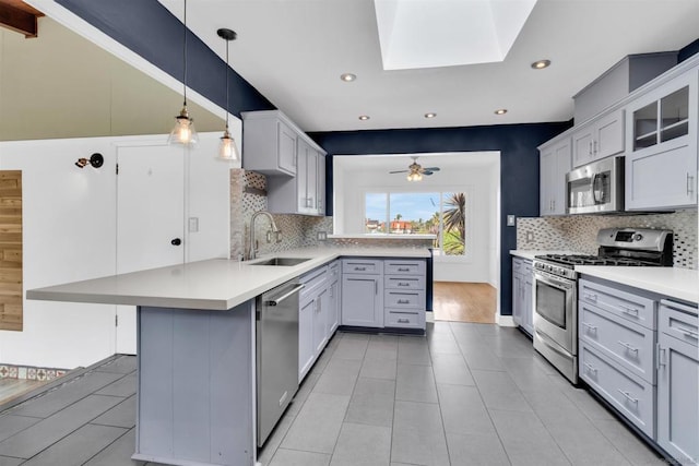 kitchen with sink, a kitchen bar, hanging light fixtures, kitchen peninsula, and stainless steel appliances