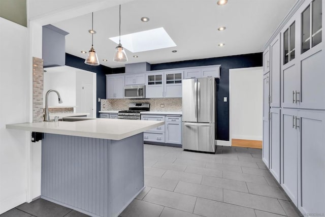 kitchen featuring sink, a skylight, stainless steel appliances, decorative light fixtures, and kitchen peninsula