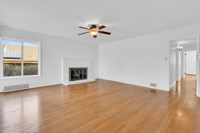 unfurnished living room featuring a fireplace, light hardwood / wood-style floors, and ceiling fan