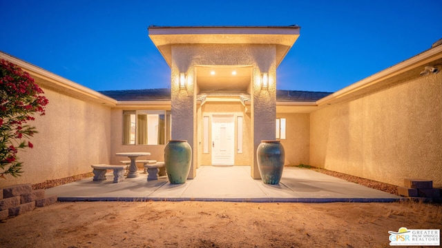 exterior entry at dusk featuring a patio