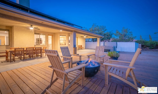 deck featuring ceiling fan and a fire pit