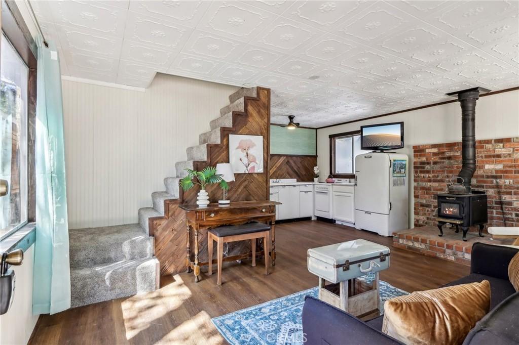 living room featuring dark wood-type flooring, a wood stove, and wooden walls