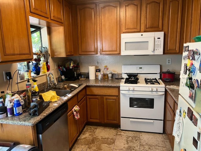 kitchen featuring white appliances, dark stone counters, and sink