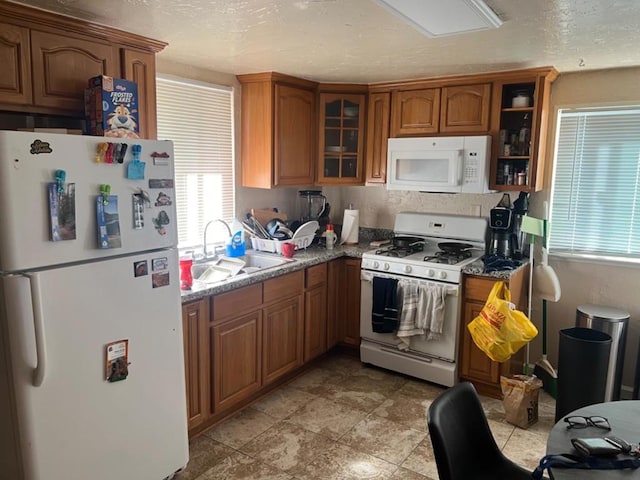 kitchen featuring white appliances, sink, a textured ceiling, and stone counters