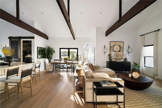 living room with beam ceiling, light hardwood / wood-style flooring, and a high ceiling