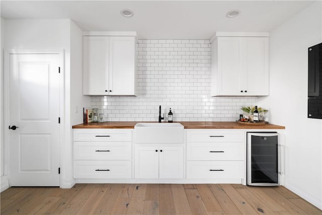 kitchen with butcher block counters, beverage cooler, and white cabinets