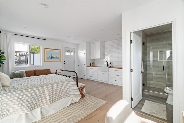 bedroom featuring ensuite bathroom, sink, and light wood-type flooring