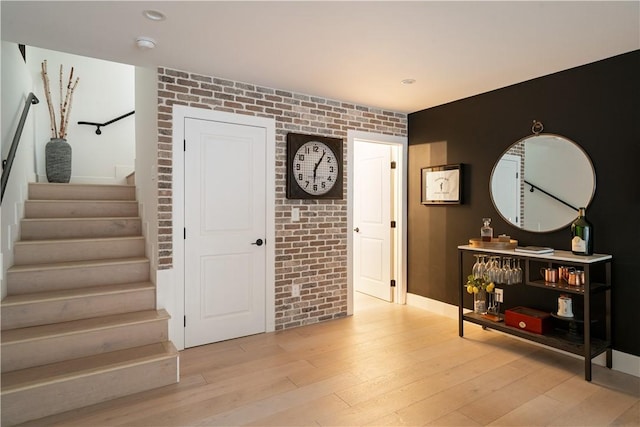 entryway featuring brick wall and light hardwood / wood-style floors