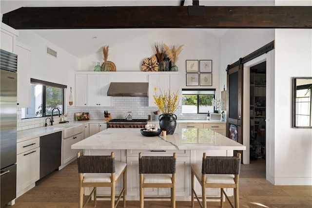 kitchen featuring a barn door, black dishwasher, a kitchen island, and white cabinets